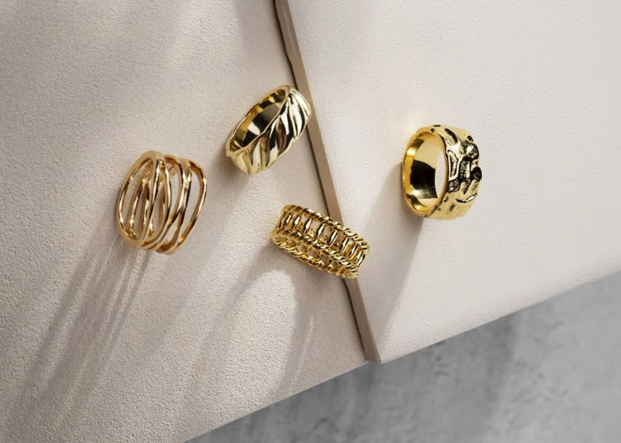 Anillos de oro variados sobre fondo claro - Contacto Rejoya