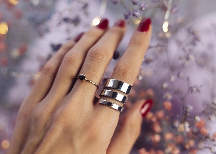 Vender Plata en Madrid Mano con anillos de plata sobre fondo floral, representando la Vender Plata en Madrid